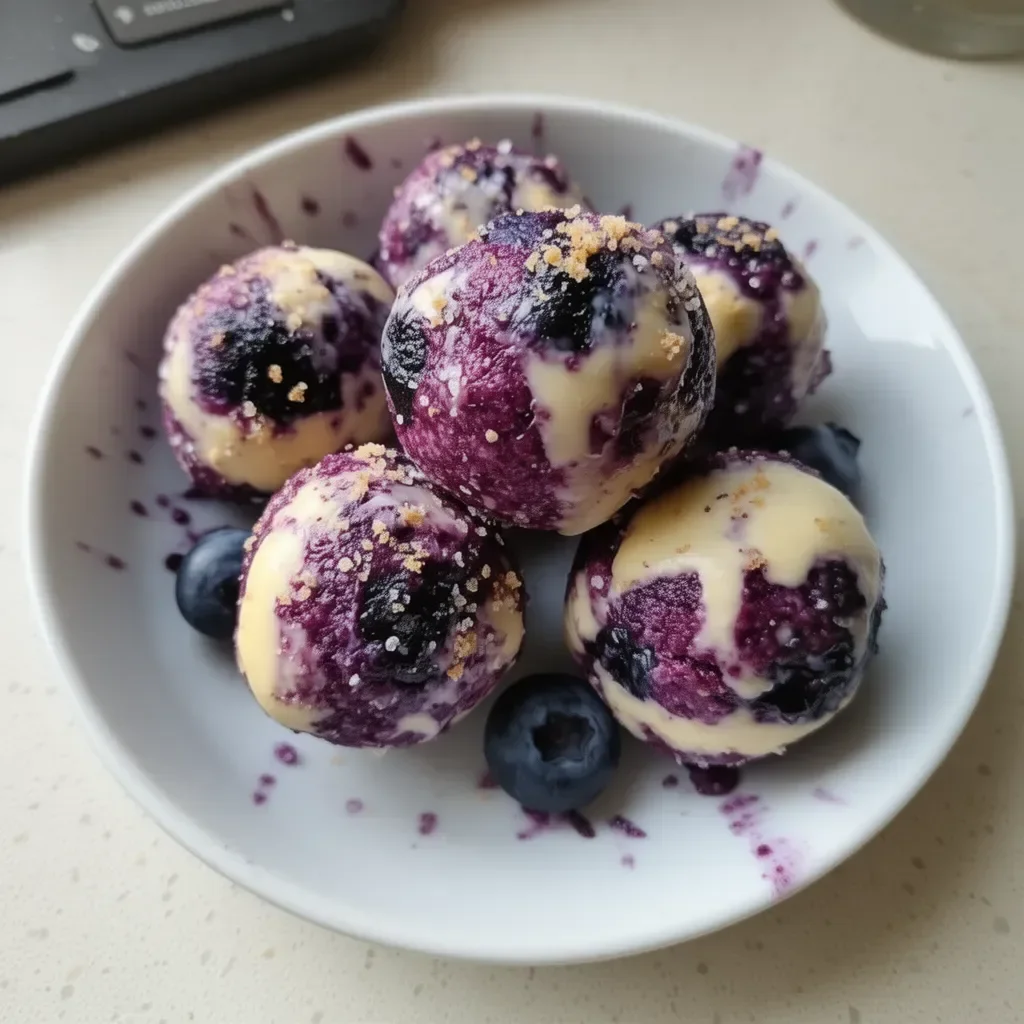 Blueberry Cheesecake Protein Bites on a white plate garnished with blueberries
