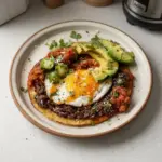 Plate of Ranch Style Eggs garnished with fresh herbs and vegetables